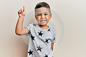 Adorable latin toddler wearing casual clothes smiling with an idea or question pointing finger up with happy face, number one