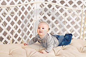 Adorable laughing baby boy in sunny bedroom. Newborn child relaxing. Family morning at home. Little kid lying on tummy