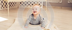 Adorable laughing baby boy in sunny bedroom. Newborn child relaxing. Nursery for young children.Family morning at home