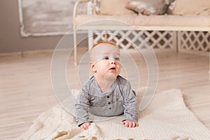 Adorable laughing baby boy in white sunny bedroom. Newborn child relaxing. Family morning at home.