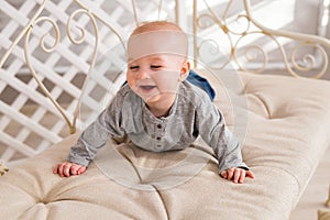 Adorable laughing baby boy in white sunny bedroom. Newborn child relaxing. Family morning at home.