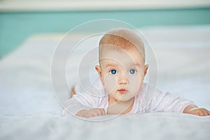 Adorable laughing baby in white sunny bedroom. Newborn infant child relaxing in bed. Textile for kids. Family morning at home. Fam