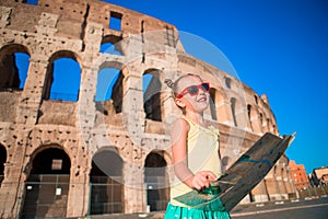 Adorable little active girl with map in front of Colosseum in Rome, Italy. Kid spending childhood in Europe