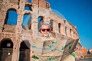 Adorable little active girl with map in front of Colosseum in Rome, Italy. Kid spending childhood in Europe