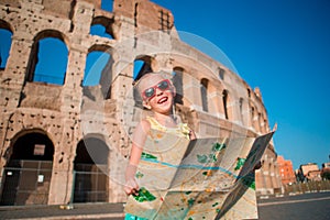 Adorable little active girl with map in front of Colosseum in Rome, Italy. Kid spending childhood in Europe