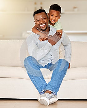 Adorable little african american boy hugging his father while relaxing on a sofa at home. Caring man with his loving son