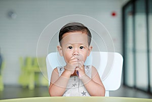 Adorable little Asian baby boy eating chocolate in the classroom