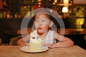 Adorable little Asian child girl blowing happy birthday cake 4 years old