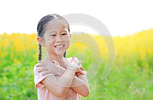 Adorable little Asian child girl feeling free with hand folded cross one`s arm in Sunhemp field with sunlight outdoor. Yellow