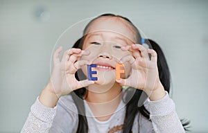 Adorable little Asian child girl holding alphabet EF Executive Functions text on her face. Education and development concept