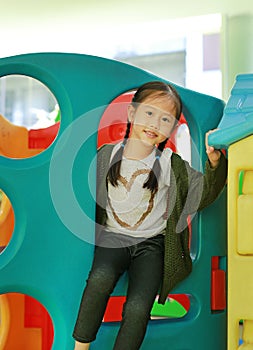 Adorable little Asian child girl playing toy playhouse at indoor playground