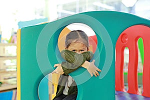 Adorable little Asian child girl playing toy playhouse at indoor playground