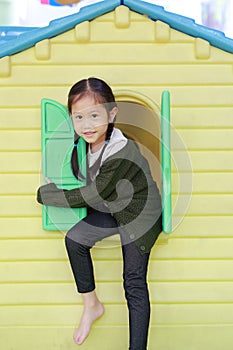 Adorable little Asian child girl playing with window toy playhouse in playground