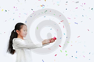 Adorable little Asian child girl shooting party popper confetti over white background with copy space