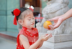Adorable little Asian girl getting sacred Orange at chinese temple in bangkok thailand, Chinese new year concept