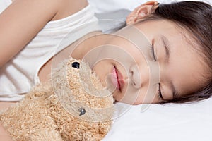 Adorable little Asian girl sleep on her bed with bear doll