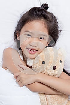 Adorable little Asian girl sleep on her bed with bear doll