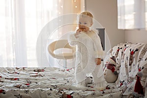 Adorable little baby boy in handknitted overall, eating cookies