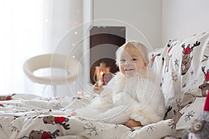 Adorable little baby boy in handknitted overall, eating cookies