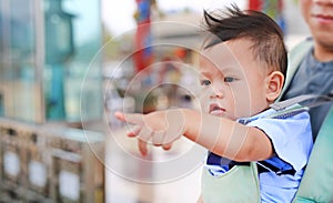 Adorable little baby boy pointing something with father carry by hipseat outdoor. Close up