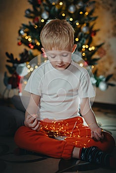 adorable little baby boy sitting in front of a christmas tree. Christmas Child Open Present Gift, Happy Baby Boy looking