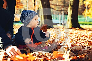 Adorable little baby child in autumn park with yellow leaves.