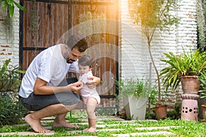 Adorable little baby daughter practice and learning walking that first time toddler girl walk on grass by father holding hands and