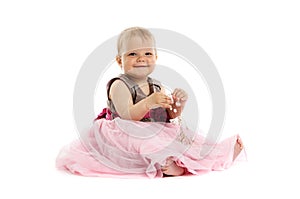 Adorable little baby girl in pink dress sitting on floor