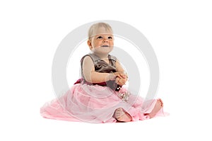 Adorable little baby girl in pink dress sitting on floor