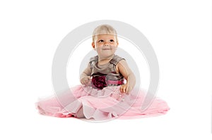 Adorable little baby girl in pink dress sitting on floor