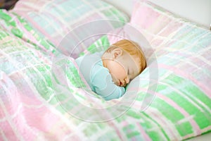 Adorable little baby girl sleeping in bed. Calm peaceful child dreaming during day sleep. Beautiful baby in parents bed