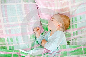 Adorable little baby girl sleeping in bed. Calm peaceful child dreaming during day sleep. Beautiful baby in parents bed