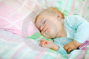 Adorable little baby girl sleeping in bed. Calm peaceful child dreaming during day sleep. Beautiful baby in parents bed
