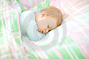 Adorable little baby girl sleeping in bed. Calm peaceful child dreaming during day sleep. Beautiful baby in parents bed