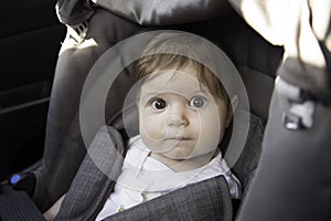 Adorable little baby sitting in car ready to ride with parents