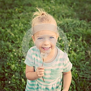 Adorable little blond girl with dandelion flower