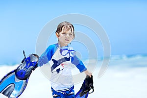 Adorable little blond kid boy having fun on tropical beach of Maldives. Excited child playing and surfing in sun