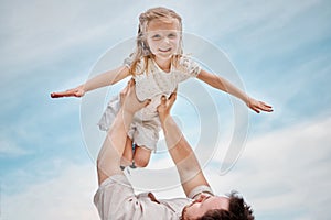 Adorable little blonde girl playing outside with her father against a clear blue sky. Cute female child smiling and