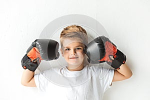adorable little boy in boxing gloves smiling at camera