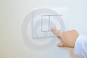 Adorable little boy child turning on the white light-switch with his finger of little hand, new generation concept