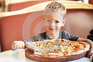 Adorable little boy eating pizza at a restaurant