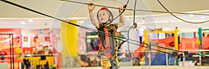 Adorable little boy enjoying his time in climbing adventure park in the mall BANNER, LONG FORMAT