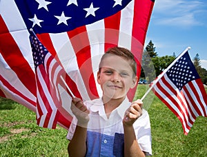 Adorable little boy holding american flag outdoors on beautiful summer day