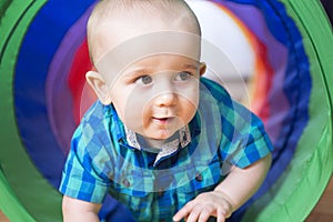 Adorable little boy playing inside a toy tunnel