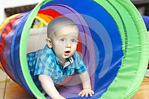 Adorable little boy playing inside a toy tunnel