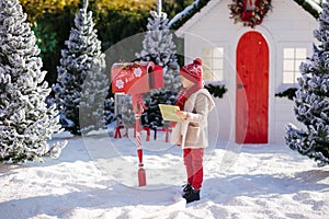 Adorable little boy with red hat and green glasses sending her letter to Santa, Christmas time