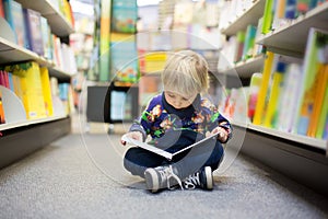 Adorable little boy, sitting in a book store