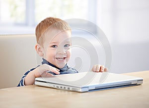 Adorable little boy smiling with laptop