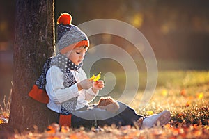 Adorable little boy with teddy bear in park on autumn day