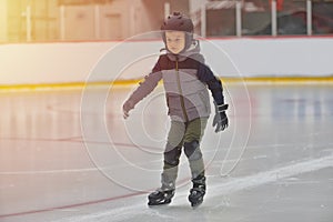 Adorable little boy in winter clothes with protections skating o photo